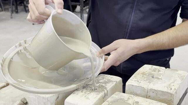 Demonstrates both casting and throwing techniques in the production of ceramic art . An artist pours liquid clay (slip) into plaster molds for ceramic pomegranate sculptures, wheel-turned clay pots.