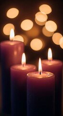 Four tall purple candles with gentle flames burning, set against a backdrop of soft, warm bokeh lights, evoking a peaceful and serene atmosphere.