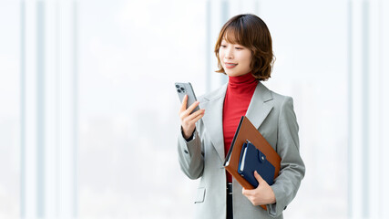 スマートフォンを確認しながら立つ日本人女性社員のモバイルワーク, Japanese office worker checking a smartphone, mobile work concept © Trickster*