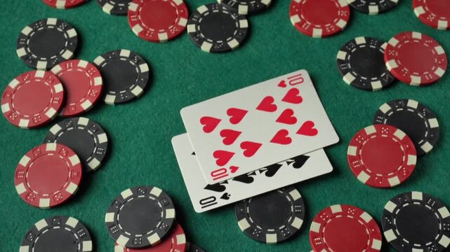 A hand places playing cards on a green felt poker table, showing a four of a kind or quads combination, with red and black poker chips scattered throughout the scene