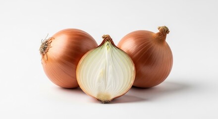 Fototapeta premium Three yellow onions, one halved, sit on a white surface, showcasing their layers