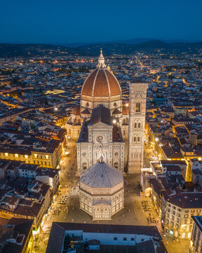 Aerial blue hour view of Florence Cathedral rising above the historic city center with soft evening light and calm sky over Tuscany, Italy