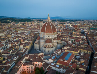 Fototapeta premium High altitude aerial view of Florence Cathedral surrounded by the dense historic cityscape of Florence, showcasing classic Tuscan rooftops and urban pattern
