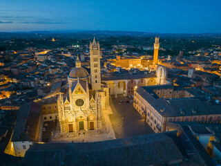 Obraz premium Wide panoramic aerial view of Siena at dusk, revealing the medieval old town, red rooftops, and surrounding Tuscan landscape. Classic Italian cityscape and UNESCO World Heritage Site