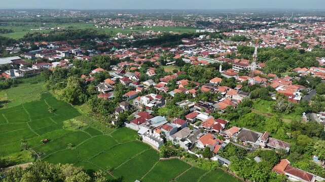 Aerial View of Densely Populated Residential Area with Telecommunication Tower and Rice Fields in Indonesia