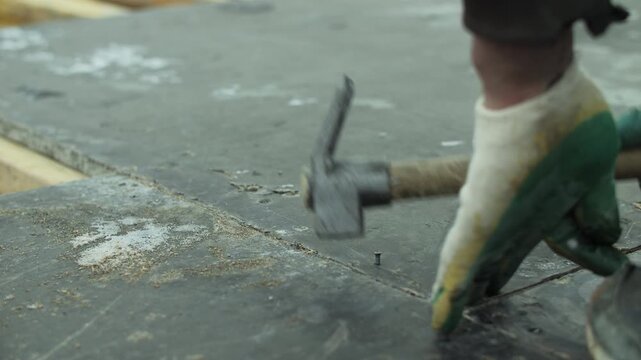 Worker hammering nail into wooden formwork during construction