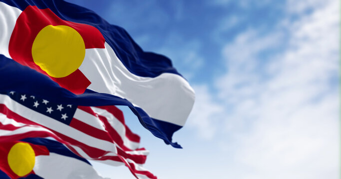 Colorado and US flags waving in the wind on a clear day
