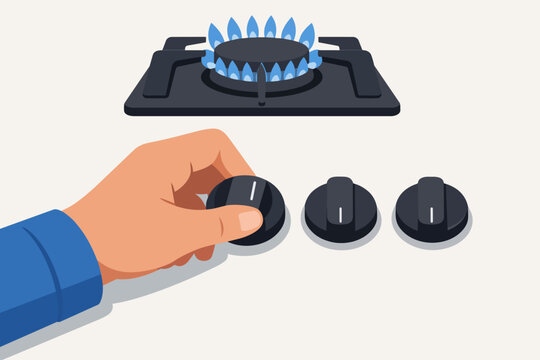 Hand adjusting gas stove knob, burner igniting blue flame in kitchen