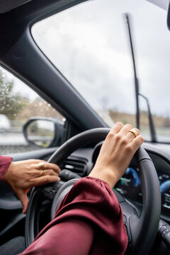 A woman is driving a car with her hands on the steering wheel