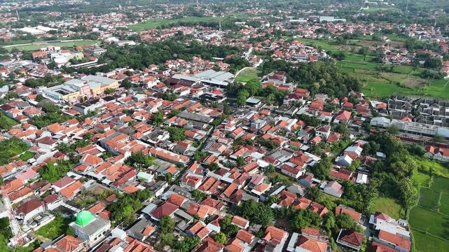 Aerial View of Dense Residential Area in Indonesia with Red Tile Roofs and Clear Blue Sky