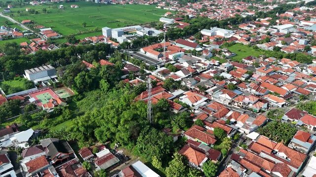 Aerial View of Densely Populated Residential Area with Telecommunication Tower and Rice Fields in Indonesia