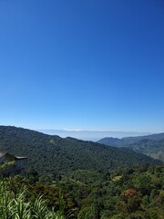 Obraz premium Mountain landscape with green forest under blue sky