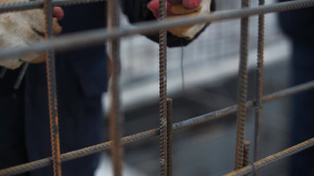 Worker tying steel rebar with wire during reinforcement work