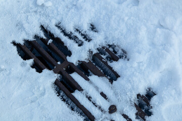 Sewer drain iron grate is covered with snow