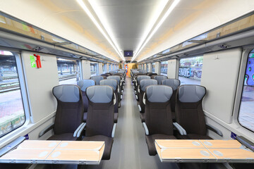 Obraz premium Chairs at second class car interior of the train, with row in front and view of modern wagon for passanger transport. Photographed in natural light.