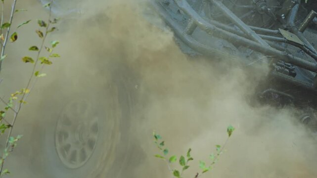 A racing Off-road vehicle races along a dirt road, kicking up a huge cloud of dust. A close-up of the harsh bugy tire highlights the power and movement of extreme racing