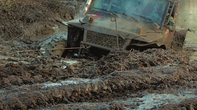 Powerful off-road vehicle stuck deep in thick mud during an extreme motorsports competition. Steam rises from the engine as a tow rope is used for recovery. Dynamic and challenging scene. Slow motion