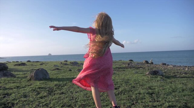 petite fille au cheveux long dansant face &agrave; la mer