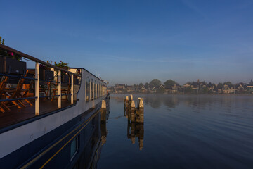 Cruise boat on Zaan River in morning mist, Netherlands