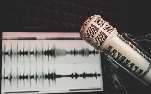Studio microphone in front of an audio waveform on a recording screen