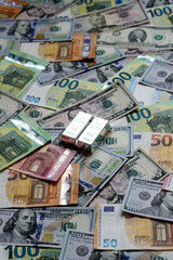 A silver bar, white metal against a backdrop of money, as a concept for the sales. A silver bar