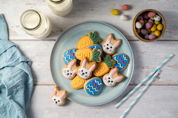Easter cookies with bottles of milk on white wooden background and mini chocolate easter candy eggs. Spring holidays background