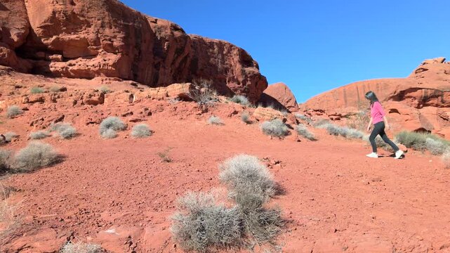 Woman on nature walk exploring vibrant red boulders of unique formation Navaho sandstone at Pioneer Park in Utah