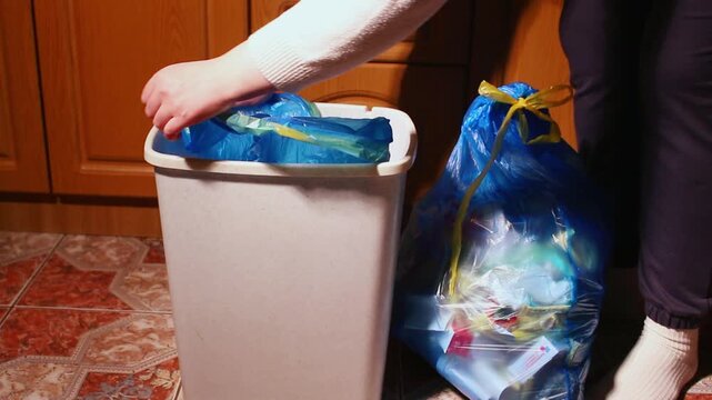 Woman placing new blue garbage bag into empty trash bin and throw away full garbage bag