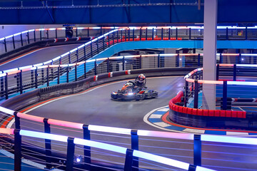 Child, driving go cart car in an indoor race track, enjoying sport © Tomsickova