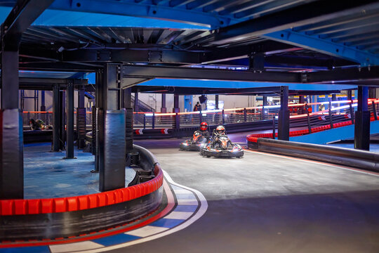 Child, driving go cart car in an indoor race track, enjoying sport