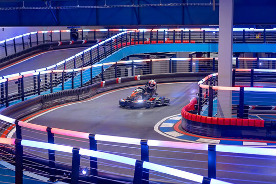 Child, driving go cart car in an indoor race track, enjoying sport