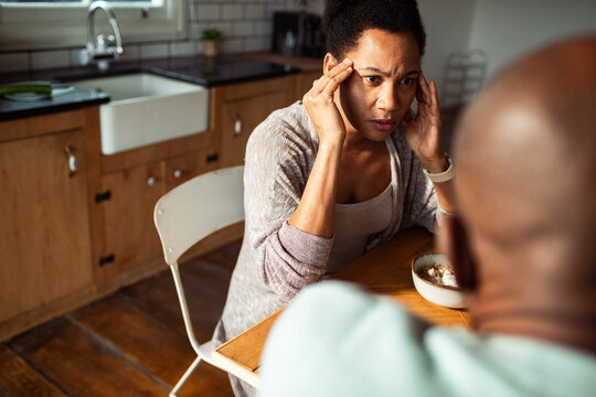 Worried woman arguing with partner at kitchen table