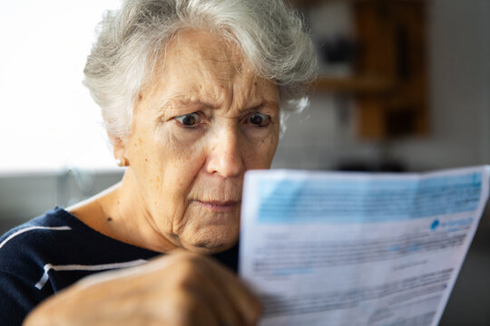 Senior woman reading a bill at home