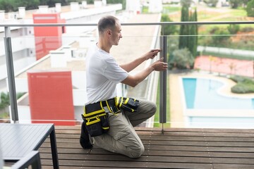  worker installing a balcony glass railling in an apartment