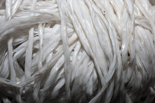 Macro view of a white polypropylene rope roll showcasing the glossy texture of synthetic fibers. This durable twine features a dense braided structure and professional finish, making it perfect for in