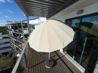 Obraz premium An inviting balcony space with comfortable seating, decorative plants, a small table, and a view overlooking modern residential buildings on a cloudy day.