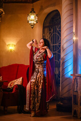 An Eastern fairy tale: a woman in red historical attire against the backdrop of a rich Eastern interior. Arabian Nights: Eastern aesthetics