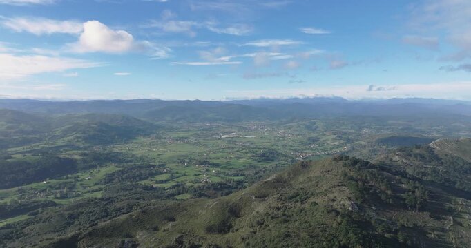 Drone flyover across layered Asturias mountains toward distant plains, cinematic northern Spain landscape featuring valleys, forests and expansive horizons