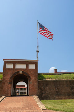 Baltimore, Maryland, US - July 26, 2023: a gate and archway to the Fort McHenry interior area with an American flag flying above