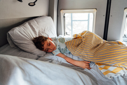 Boy child sleeping comfortably in camper van bed
