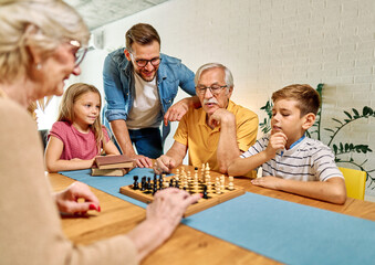 Portrait of a three generation family, grandparents, parents and children playing chess and having fun at home