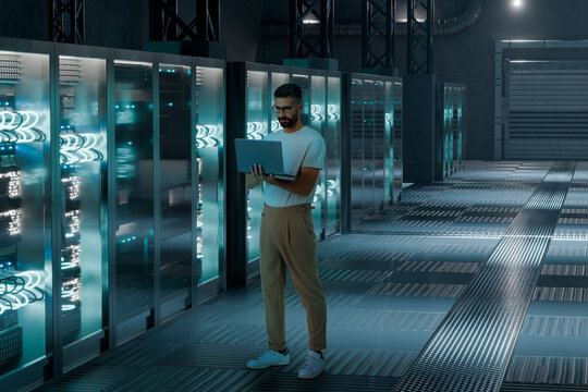 IT specialist man working with laptop inside 3D server facility