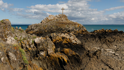 Kreutz auf einem Felsen an der K&uuml;ste mit dramatischen Wolken im Hintergrund