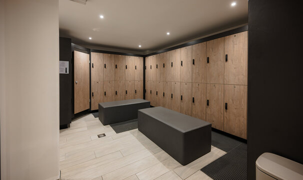 Modern gym locker room with wooden lockers and benches