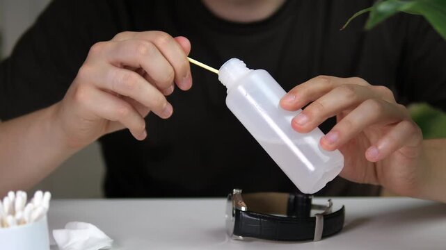 Meticulous luxury watch cleaning process. Close-up of hands using a cotton swab and solution to polish a classic timepiece. Perfect for horology, product maintenance, and restoration tutorials. High