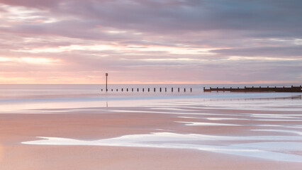 Fototapeta premium Sunrise and colourful morning light on Blyth Beach on the coast of Northumberland, England, UK.