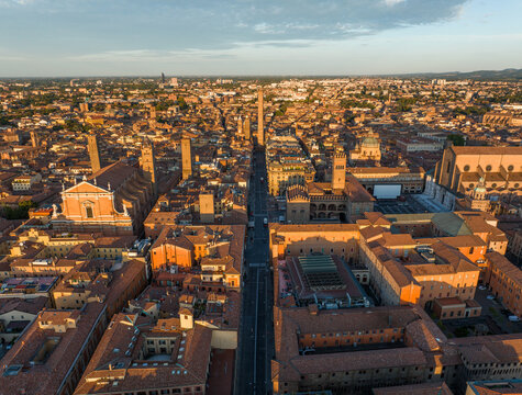 Aerial sunset view of Bologna with warm golden light illuminating the historic skyline and Asinelli Tower. Evening colors enhance the medieval rooftops of this iconic Italian city