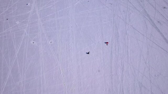 Aerial drone footage of snowmobiles intricate curved tracks patterns textures on fresh winter snow under bright sunny sunlight. Ice fishing sport on frozen lake Simcoe, Cook&rsquo;s Bay, Innisfil, Canada.