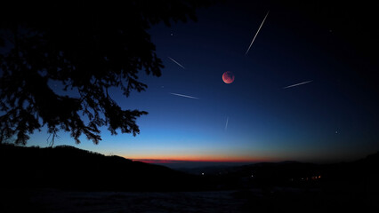 Blue hour time with lunar eclipse, stars and planets above landscape silhouettes. © astrosystem