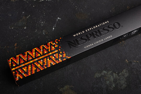 A unique Nespresso coffee packing box sits on a dark surface. The box features orange dots and a pattern on the top. This design showcases Vienna Linizio Lungo coffee